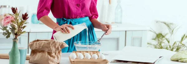 Vista recortada de pin up niña añadiendo leche de botella a los ingredientes para hacer masa — Stock Photo