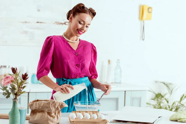Elegant pin up girl mixing ingredients for making dough and looking at camera — Stock Photo