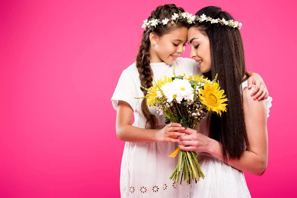 Hermosa madre feliz e hija en vestidos blancos y coronas con flores aisladas en rosa — Stock Photo