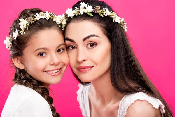 Bela mãe feliz e filha em coroas florais sorrindo para a câmera isolada em rosa — Fotografia de Stock