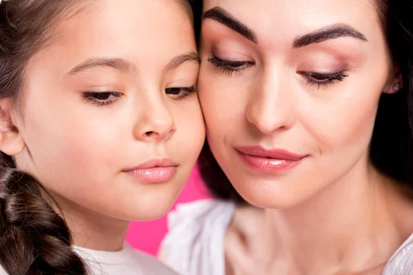 Vista de cerca de la hermosa madre y la hija mirando hacia abajo aislado en rosa - foto de stock