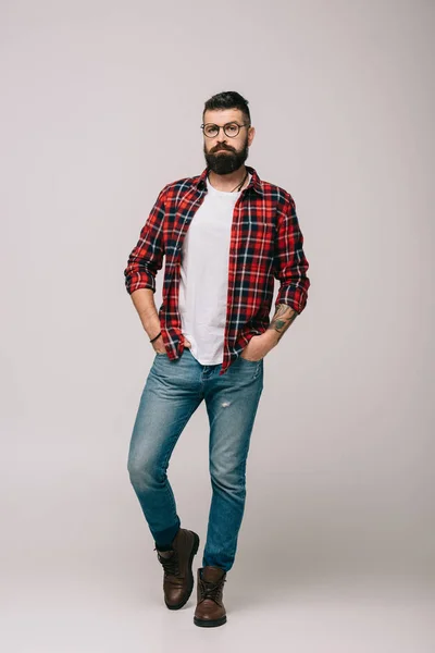 Schöner selbstbewusster Mann posiert in kariertem Hemd isoliert auf grau — Stockfoto