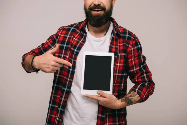 Vista recortada del hombre apuntando a la tableta digital con pantalla en blanco, aislado en gris - foto de stock