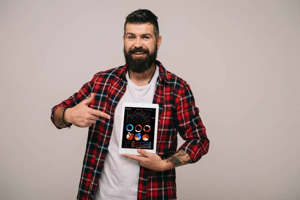 Uomo sorridente che punta al tablet digitale con app infografica, isolato su grigio — Foto stock