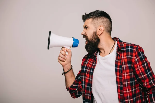 Angry bearded man in checkered shirt screaming into megaphone, isolated on grey — Stock Photo