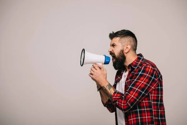 Angry bearded man in checkered shirt shouting into megaphone, isolated on grey — Stock Photo