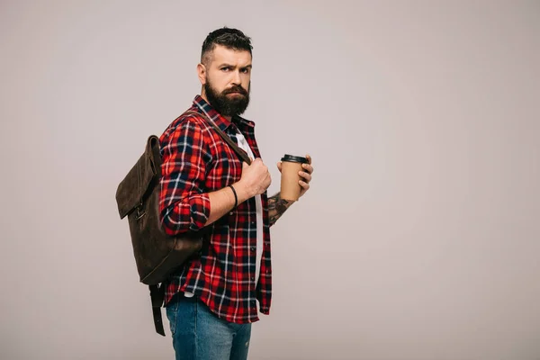 Hombre guapo serio en camisa a cuadros sosteniendo taza de papel de café aislado en gris - foto de stock