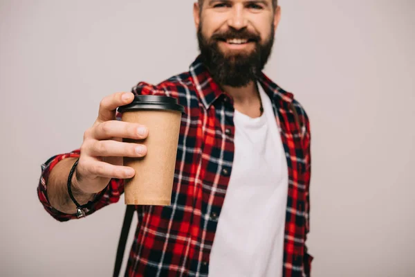 Bärtiger lächelnder Mann im karierten Hemd mit Kaffee to go auf grau — Stockfoto