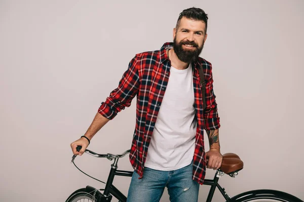 Красивий усміхнений чоловік позує з велосипедом ізольовано на сірому — стокове фото