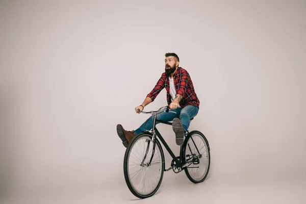 Бородатий збуджений чоловік їде на велосипеді ізольований на сірому — стокове фото