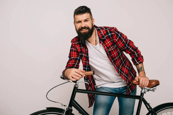 Bell'uomo barbuto sorridente in posa con bicicletta isolata su grigio — Foto stock
