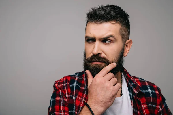 Verdächtiger bärtiger Mann im karierten Hemd denkt isoliert auf grau — Stockfoto