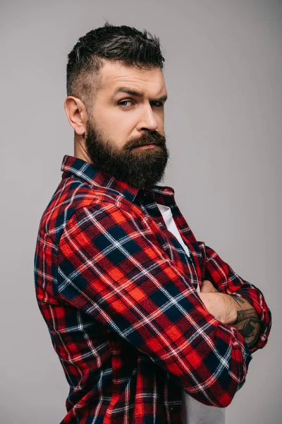 Hombre barbudo sospechoso con camisa a cuadros aislado en gris - foto de stock