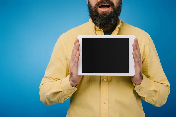 Vista recortada del hombre excitado mostrando tableta digital con pantalla en blanco, aislado en azul - foto de stock