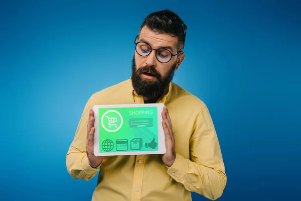 Interested bearded man looking at digital tablet with shopping app, isolated on blue — Stock Photo