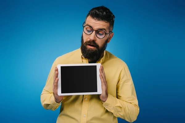 Homem barbudo interessado olhando para tablet digital com tela em branco, isolado em azul — Fotografia de Stock