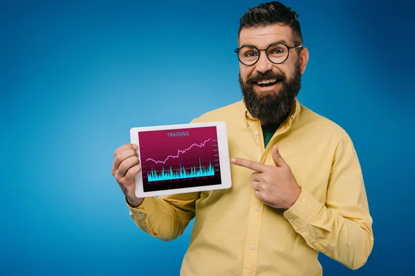 Щасливі бородатого мужчини вказуючи на Цифрова табличка з tariding app, ізольовані на блакитному — стокове фото