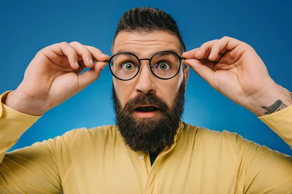Потрясенный бородатый мужчина в очках, изолированных на голубом — стоковое фото