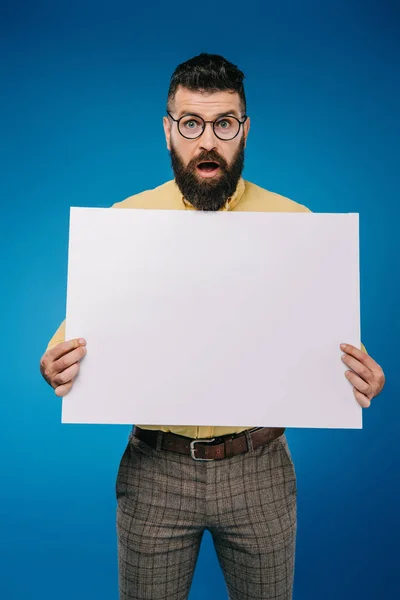 Impactado hombre sosteniendo cartel en blanco aislado en azul - foto de stock