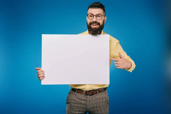 Fröhlicher bärtiger Mann zeigt auf leere Tafel auf blauem Grund — Stockfoto