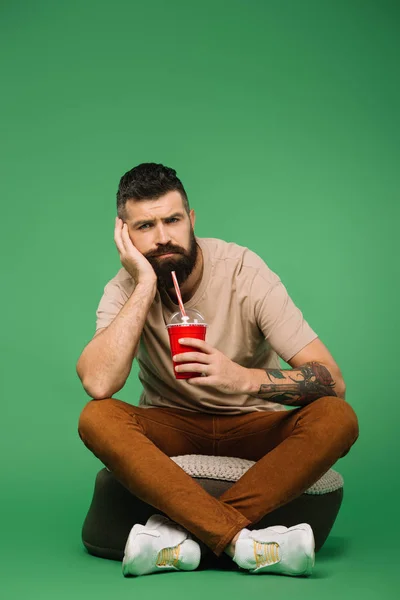 Handsome bored man holding soda on green — Stock Photo