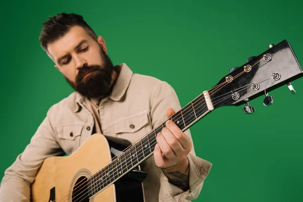 Homem bonito tocando na guitarra acústica, isolado no verde — Fotografia de Stock