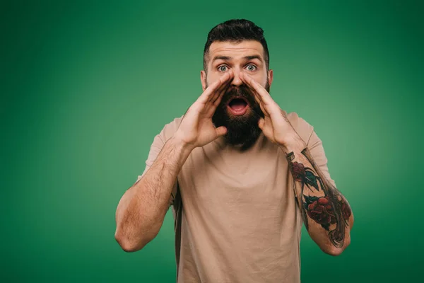 Handsome tattooed man shouting isolated on green — Stock Photo