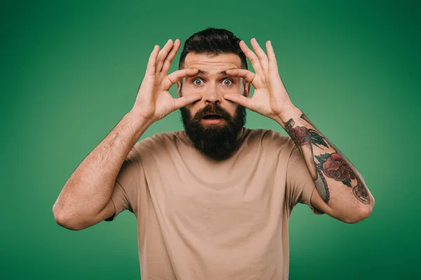 Hombre barbudo guapo mantener los ojos abiertos aislados en verde - foto de stock