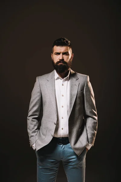 Hombre de negocios barba posando en chaqueta gris aislado en marrón - foto de stock