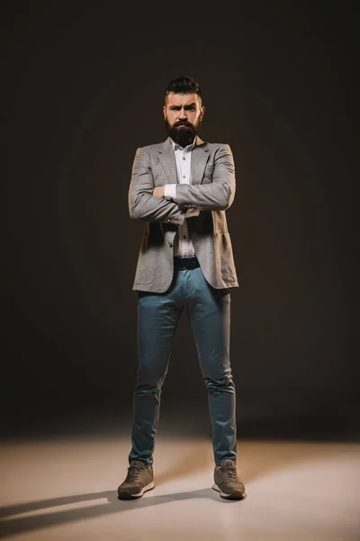 Handsome businessman standing with crossed arms on brown — Stock Photo