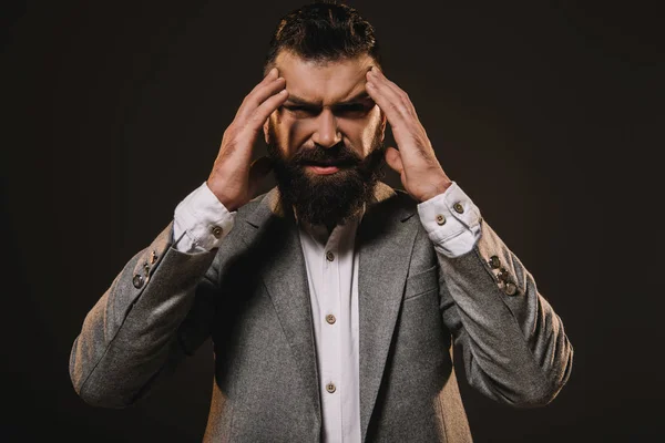 Elegante hombre de negocios barba con dolor de cabeza aislado en marrón - foto de stock