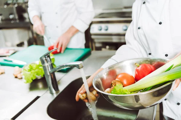 Cropped view of female chef washing vegetables in restaurant kitchen — Stock Photo