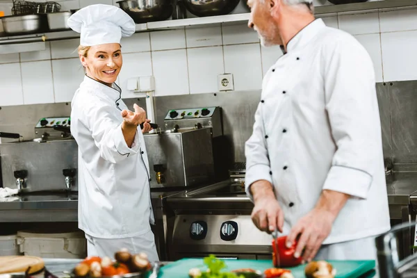 Female and male chefs in double-breasted jackets during cooking in restaurant kitchen — Stock Photo