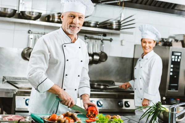 Selektiver Fokus männlicher und weiblicher Köche in Uniform bei der Zubereitung von Speisen in der Restaurantküche — Stockfoto