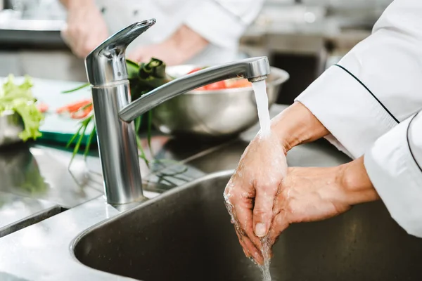 Cropped view of female chef washing hands in restaurant kitchen — Stock Photo