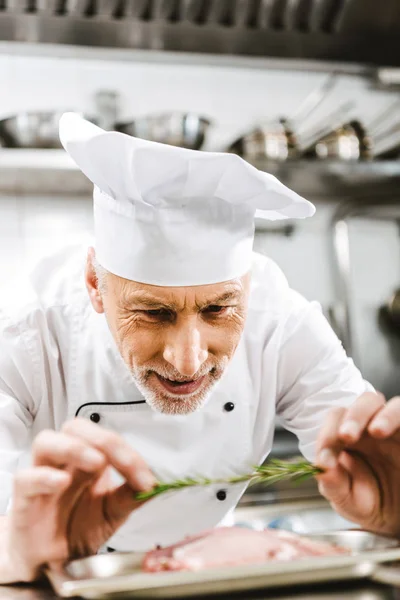 Küchenchef in Uniform dekoriert Gericht mit Kräutern in Restaurantküche — Stockfoto