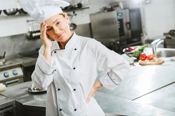 Hermosa mujer cansada chef en uniforme con dolor de cabeza en la cocina del restaurante - foto de stock