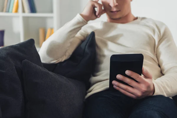 Ausgeschnittene Ansicht eines fokussierten Mannes, der zu Hause E-Books liest — Stockfoto