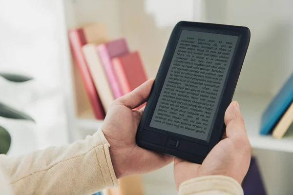 Ausgeschnittene Ansicht eines Mannes, der mit E-Reader in der Nähe des Bücherregals steht — Stockfoto