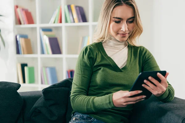 Bella donna borchie con ebook mentre seduto sul divano — Foto stock