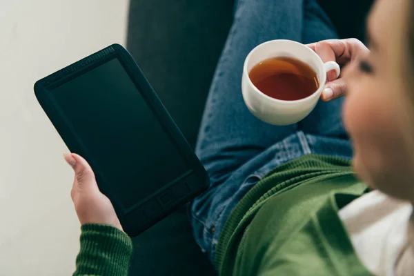 Messa a fuoco selettiva della donna che tiene ebook con schermo bianco e tazza con tè in mano — Foto stock