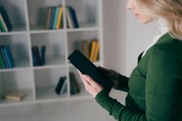 Ausgeschnittene Ansicht einer Frau mit E-Reader in der Nähe des Bücherregals — Stockfoto
