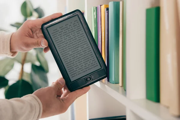 Cropped view of man taking ebook from bookshelf — Stock Photo