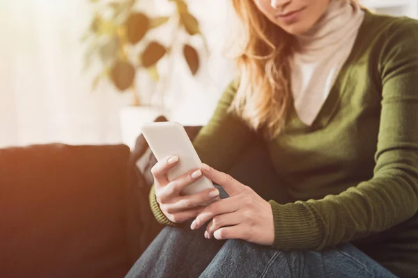 Ausgeschnittene Ansicht einer Frau, die ihr Smartphone zu Hause benutzt — Stockfoto
