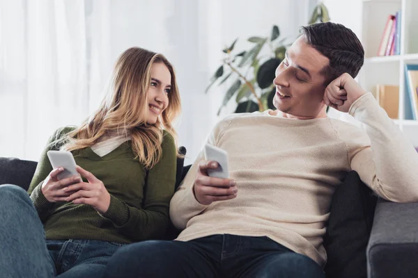 Fröhliche Frau schaut Freund an, während sie zu Hause auf dem Sofa sitzt — Stockfoto