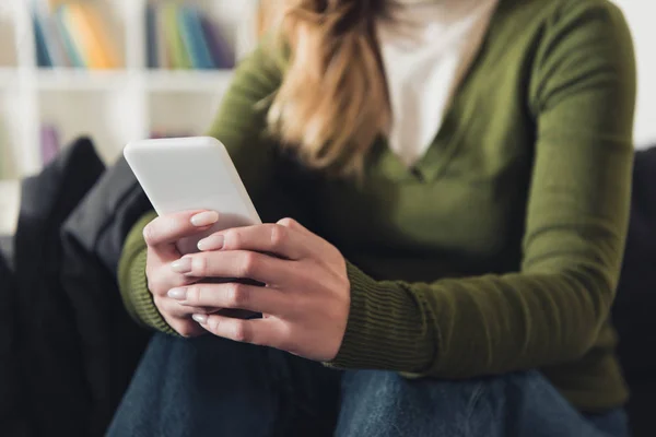 Vista recortada de la mujer sosteniendo el teléfono inteligente en casa - foto de stock