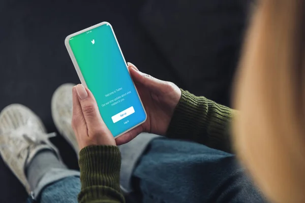 Foyer sélectif de la femme tenant smartphone avec application twitter à l'écran — Photo de stock