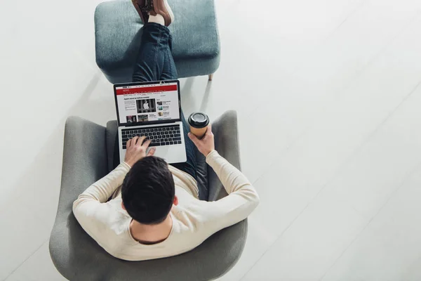 Vista superior del hombre usando el ordenador portátil con el sitio web de noticias de la BBC en la pantalla - foto de stock