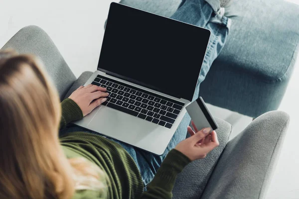 Vue recadrée de la femme en utilisant un ordinateur portable avec écran vierge tout en tenant la carte de crédit — Photo de stock