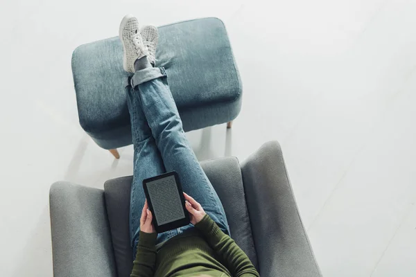 Vista dall'alto di donna borchie con ebook e seduta in poltrona a casa — Foto stock